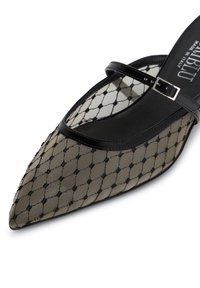 Pompa in rete nera e beige con punta affilata, caratterizzata da un design a rete, cinturino con dettaglio fibbia e interno liscio.