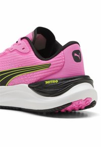 Nike hardloopschoen in roze mesh met zwarte en neongele accenten. Voorzien van een opgevulde zool en een gestructureerde hak met NITRO-branding.