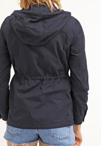 Navy blue windbreaker jacket with a hood, cinched waist, and elastic cuffs, made from lightweight fabric; features no visible hardware.