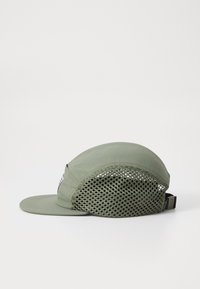Green cap with a mesh back, curved brim, and adjustable strap. Features a patch logo on the front and textured fabric.