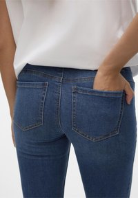 Blå denimjeans med strukturerade bakfickor, kontrasterande sömmar och en figurnära design. Bomullstyg med en mjuk textur.