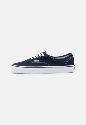 Baskets basses en toile Vans bleu marine avec lacets blancs, semelle en caoutchouc blanche et étiquette avec logo Vans sur la paroi latérale.