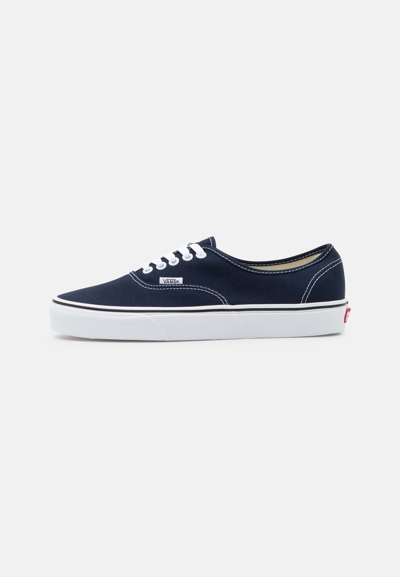 Baskets basses en toile Vans bleu marine avec lacets blancs, semelle en caoutchouc blanche et étiquette avec logo Vans sur la paroi latérale.