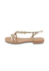 Metalen gouden platte sandaal met bloemaccenten, slanke bandjes en een gladde beige voetbed. Heeft een verstelbare enkelband en een houtachtige zool.