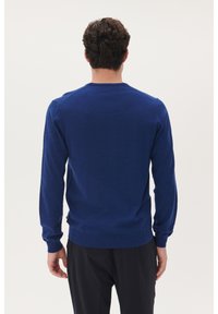 Modra dolga majica s long sleeves in okroglim izrezom, z ribastimi manžetami in robom. Gladka tekstura s prilegajočim dizajnom, prikazana s hrbtne strani.