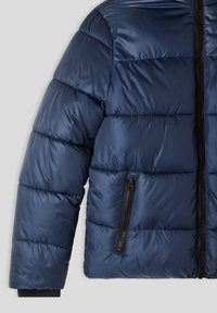 Granatowa kurtka puchowa o pikowanej fakturze, z zamkiem błyskawicznym z przodu i boczną kieszenią na zamek. Zawiera czarne akcenty wzdłuż zamka.