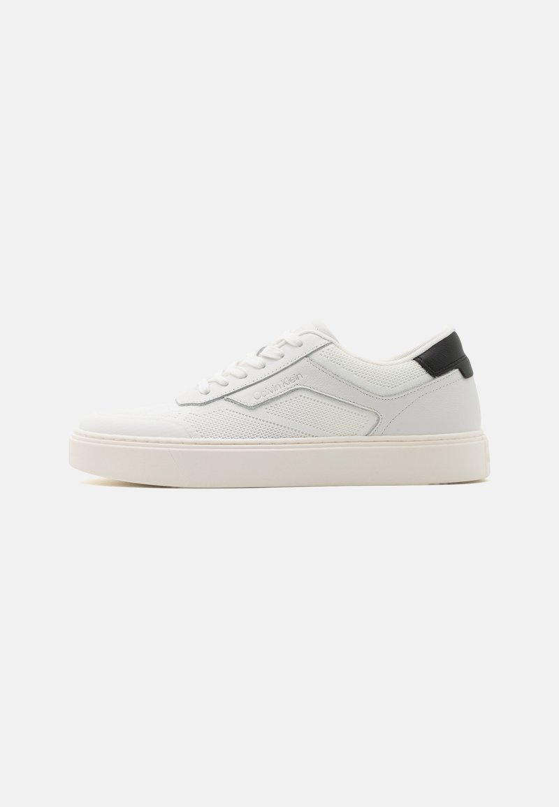 Sneaker bianca con tomaia testurizzata e dettagli lisci, con un tab sul tallone nero, chiusura con lacci e una suola spessa bianca.
