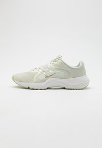 Light green athletic shoes featuring a breathable mesh upper, textured accents, a white sole with a slight curve, and a gold logo detail.