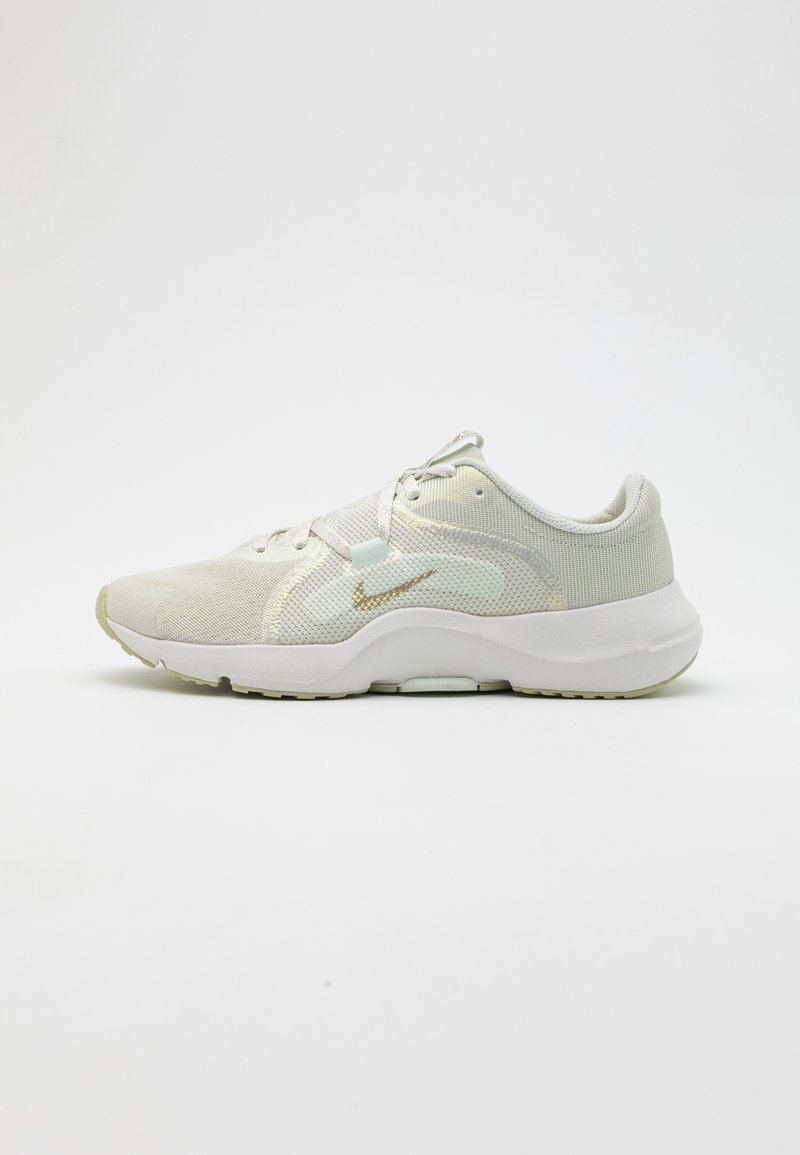 Light green athletic shoes featuring a breathable mesh upper, textured accents, a white sole with a slight curve, and a gold logo detail.