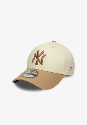 Casquette de baseball beige avec une visière couleur sable, ornée d'un logo brodé en relief marron. Comprend des trous de ventilation et une sangle réglable.