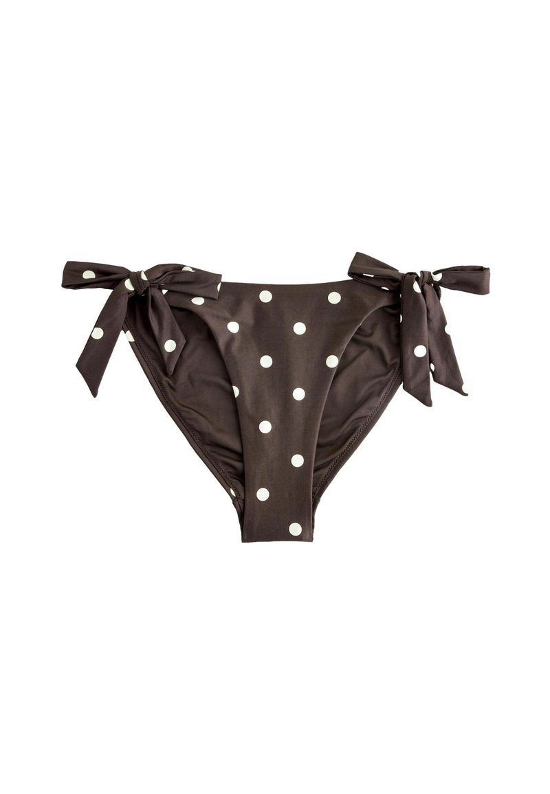 Barna bikini alsórész fehér pöttyökkel és oldalt megkötött pántokkal, fehér háttérrel.