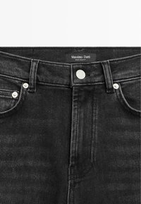 Black denim jeans with a mid-rise waist, featuring silver button hardware, belt loops, and a tag stating "Massimo Dutti, Made in Egypt."