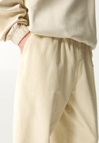 Lichtbeige corduroy broek met een ribbelstructuur, elastische tailleband en zijzakken, gecombineerd met een bijpassend langemouwen top.