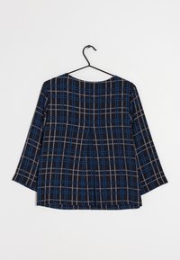 Top a quadretti blu navy con maniche a trequarti, caratterizzato da un motivo di quadrati grigi e blu, tessuto texturizzato e scollatura rotonda.