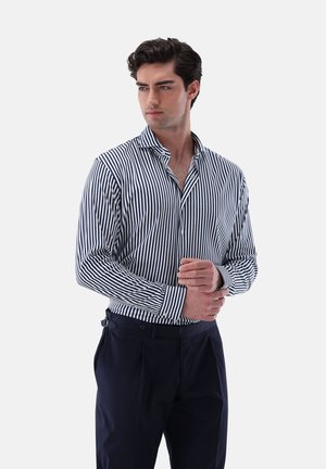 Striped shirt with navy and white vertical stripes, button-up collar, long sleeves, and a tailored fit, paired with dark trousers.