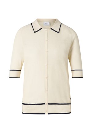 Kremowy kardigan na guziki z krótkim rękawem, wykończony czarnym paskiem na kołnierzu, rękawach i dolnej krawędzi.