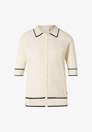 Kremowy kardigan na guziki z krótkim rękawem, wykończony czarnym paskiem na kołnierzu, rękawach i dolnej krawędzi.