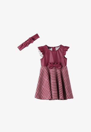 Tmavě červené šaty s volánkovými rukávy, mašlí v pase a sukní v vzoru kostičky. Součástí je i čelenka s mašlí ve stejném vzoru.