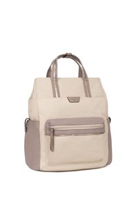 Beige canvas rugzak met donkerder taupe accenten, een ritsvak aan de voorkant en dubbele handgrepen aan de bovenkant. Heeft een gestructureerde vorm en een gladde textuur.
