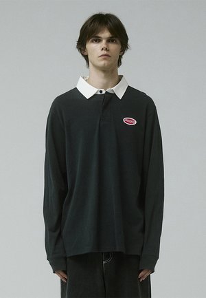 Dark long-sleeve polo shirt with a white collar, featuring a small red logo on the chest and a relaxed fit. Soft cotton material.