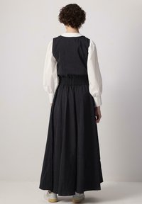 Must musta pikk kleit volangvööga, tagaküljel kinnine ja A-line disain. All on kontrastne valge pikkade varrukatega särk.