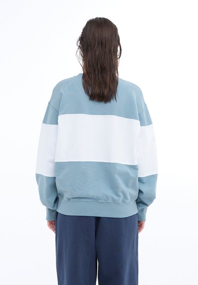 Light blue and white color-blocked sweatshirt with a rounded neck and ribbed cuffs, featuring a relaxed fit and soft texture.
