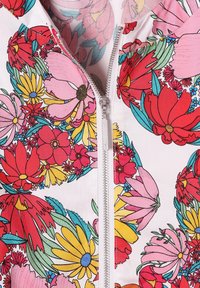 Blomster zip-up jakke med en hvid bund og røde, pink og gule blomster. Glat stof med en metallisk lynlås foran.