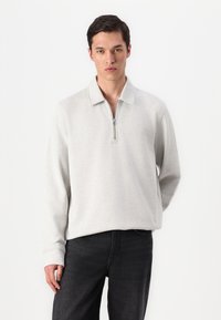 Light gray long-sleeve pullover with a zipper collar, made of soft fabric. The design features a relaxed fit and ribbed cuffs.