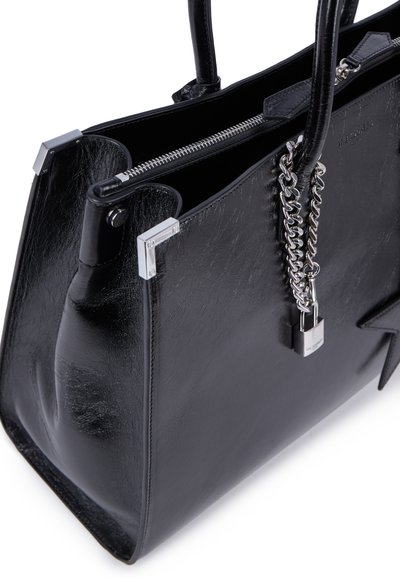 Borsa a tracolla nera in pelle con una texture liscia, dettagli in catena argentata e chiusura con zip. Presenta accessori metallici quadrati e un dettaglio con logo.