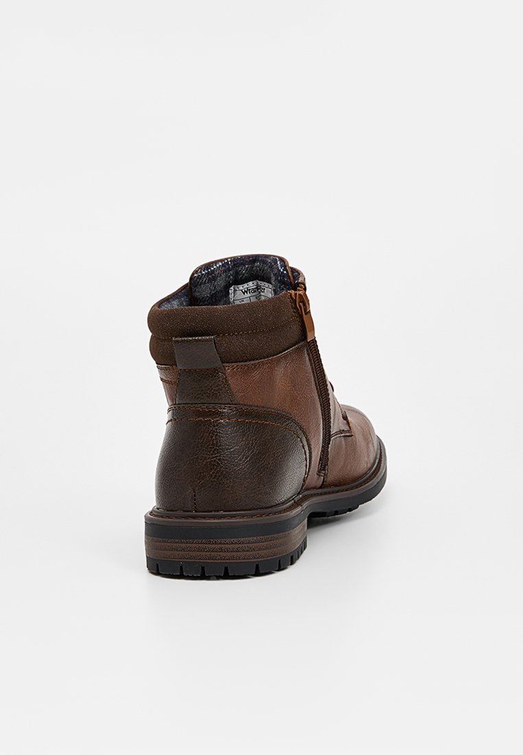 Botín de cuero marrón hasta el tobillo con un acabado texturizado, que presenta una cremallera lateral, un cuello acolchado y una suela de goma con surcos de tracción.