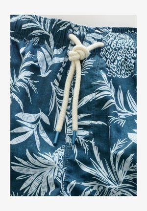 Shorts de baño con estampado floral en tonos azules, que presentan una cintura ajustable con un cordón de color beige y puntas de plástico azul. La tela tiene una apariencia texturizada.