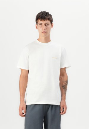 White cotton t-shirt with a crew neck, short sleeves, and a small gold logo on the left chest. Worn with dark gray shorts.