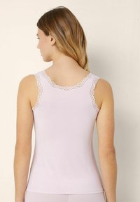 Hellrosa Tanktop mit Spitzenbesatz am Ausschnitt und den Trägern, das eine figurbetonte Passform und eine weiche Textur für zusätzlichen Komfort bietet.