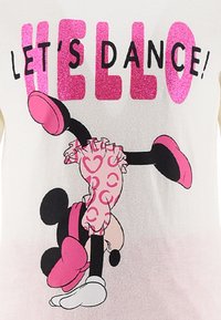 Camiseta blanca con texto en purpurina rosa "¡BAILEMOS!" y una gráfica de un personaje de dibujos animados con un atuendo rosa con volantes y un lazo.