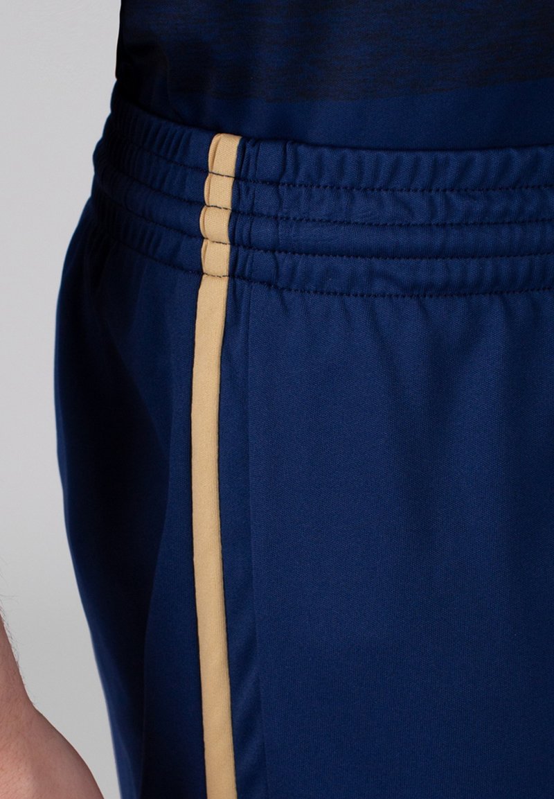 Shorts de sport navy avec taille élastique, dotés d'une bande dorée sur le côté. Le matériau est lisse et léger avec une finition texturée.