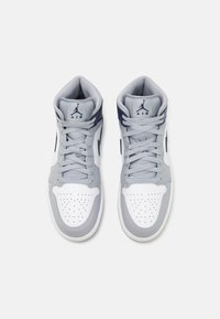 Tenisky s vysokým střihem, které mají bílý a světle šedý kožený svršek s námořnickými akcenty, perforovanou špičku a šedé tkaničky. Logo na jazyku.