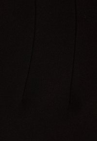 Gros plan sur un tissu noir texturé avec deux coutures verticales.
