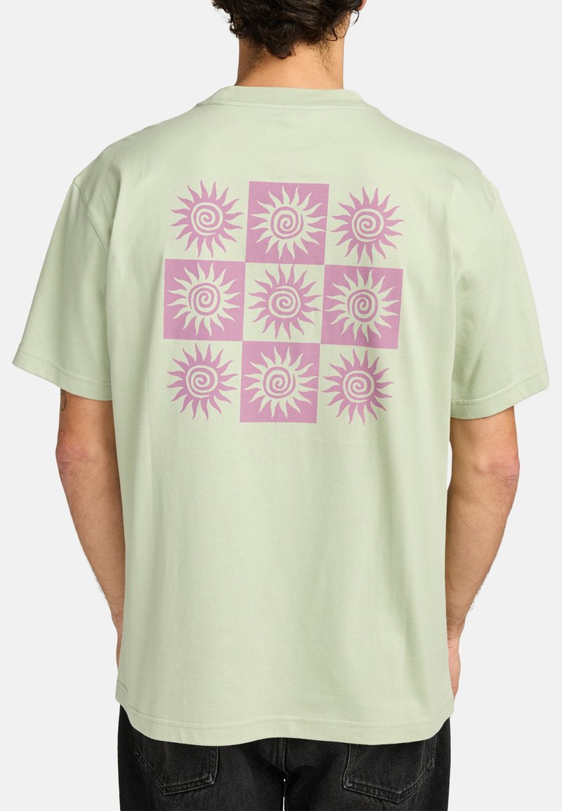 Lichtgroene katoenen t-shirt met een groot roze zonnenpatroon op de rug, met een rooster van wervelende zonontwerpen in negen vakken.