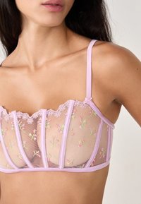 Lilac mesh bralette with floral embroidery, soft lace trim, and adjustable straps; features sheer panels and structured seams.