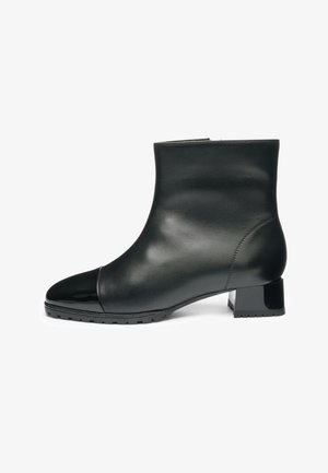 Zwarte leren enkellaars met een lage blokhak, glanzende neuskap en profielzool, gezien van de buitenkant.