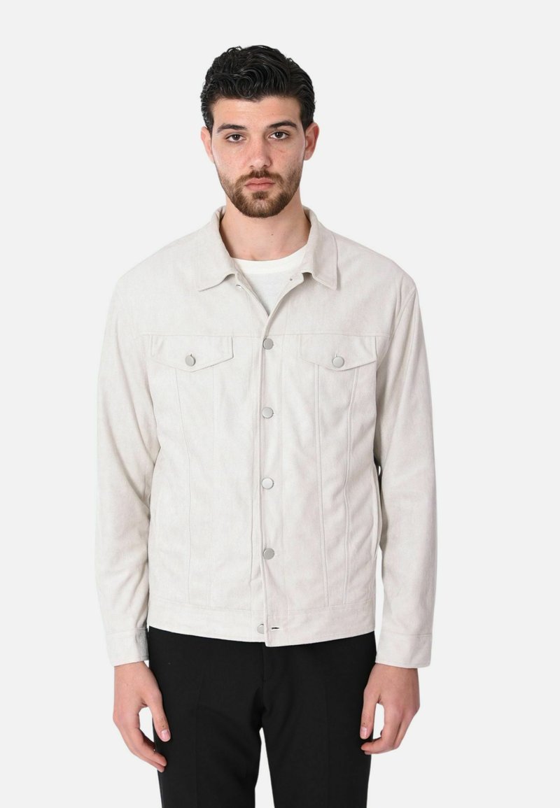 Giacca di jeans beige chiaro con colletto, due tasche sul petto, chiusura frontale con bottoni argentati e dettagli di cucitura verticale.