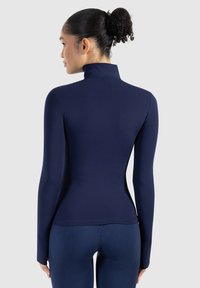Top de manga larga azul marino con cuello alto, hecho de una tela suave y elástica. Presenta un diseño ajustado y construcción sin costuras.