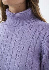 Lila gestrickter Rollkragenpullover mit einem Zopfstrickdesign und gerippten Akzenten am Kragen und Saum, das eine weiche, strukturierte Oberfläche zeigt.