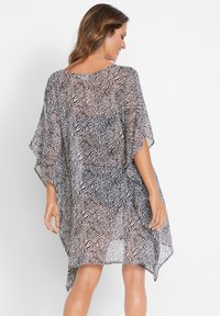 Copertura in stile kimono trasparente con stampa animale monocromatica e motivi geometrici, vestibilità ampia e maniche larghe. Tessuto morbido e leggero.