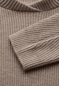 Maglione beige lavorato a maglia con texture a costine, dotato di scollatura a V e colletto leggermente arrotolato, realizzato in un morbido tessuto simile alla lana.