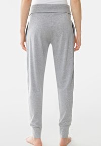 Grå bomullssweatpants med bred elastisk midja, smalnande ben och öppna sidfickor. Tyget har en mjuk och slät textur.