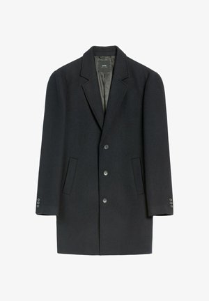 Ciemnooliwowa wełniana kurtka z wywijanym kołnierzem, podwójnym zapięciem, dwoma przednimi kieszeniami oraz mankietami zapinanymi na guziki. Gładka faktura i dopasowany krój.