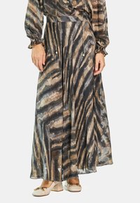 Maxikleid aus transparentem Stoff mit einem beigen, schwarzen und braunen Zebramuster. Lange Ärmel und Kordelzugbund mit Perlenakzenten.