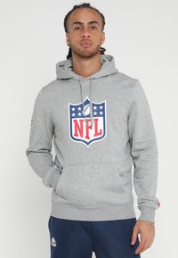 Sudadera gris con un bolsillo tipo canguro en el frente, con un logo de la NFL en rojo, blanco y azul. Tejido suave con puños y dobladillo acanalados.