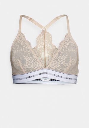 Bralette en dentelle beige clair avec des bonnets triangulaires, des bords festonnés et une bande élastique blanche avec le logo "GUESS". Bretelles réglables.